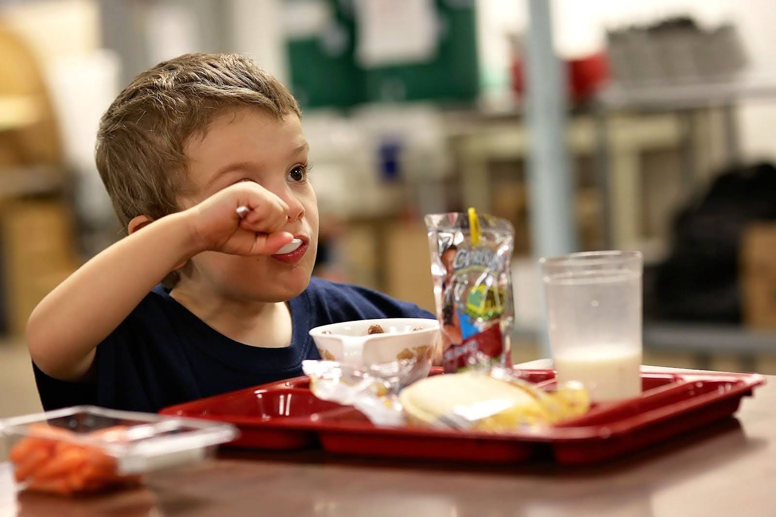 A young boy eating lunch from a Salvation Army cafeteria.