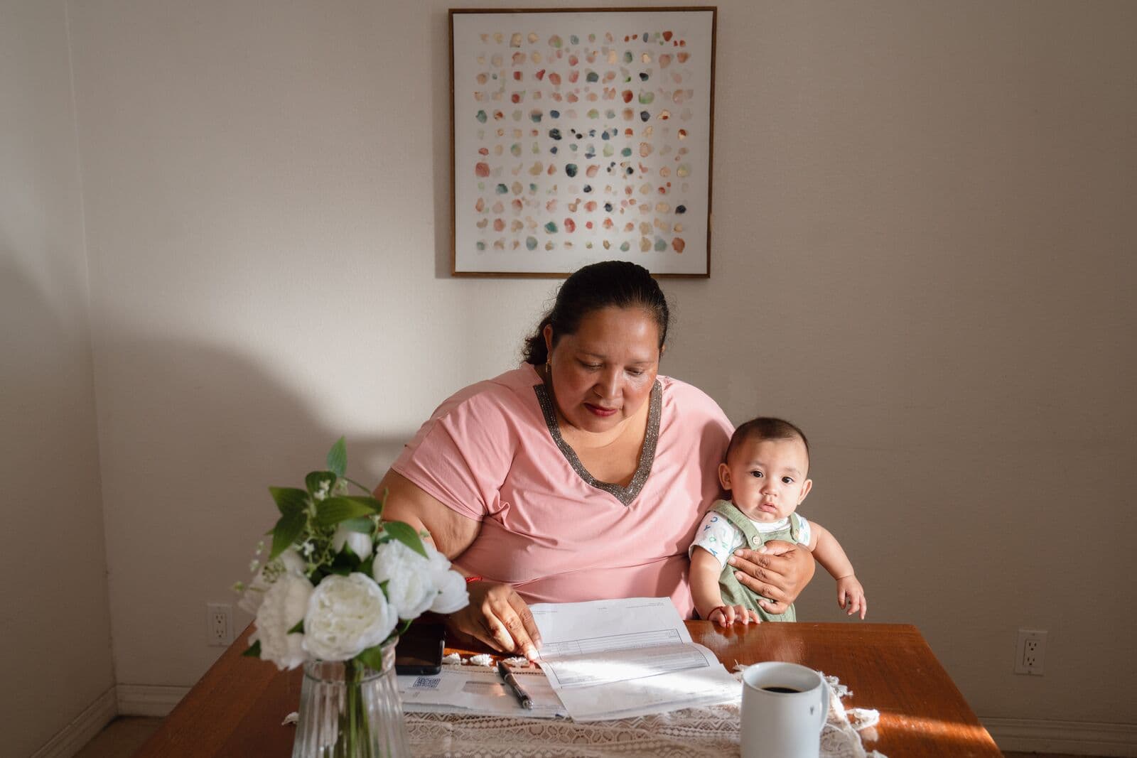 A mother holding her baby while overlooking her bills