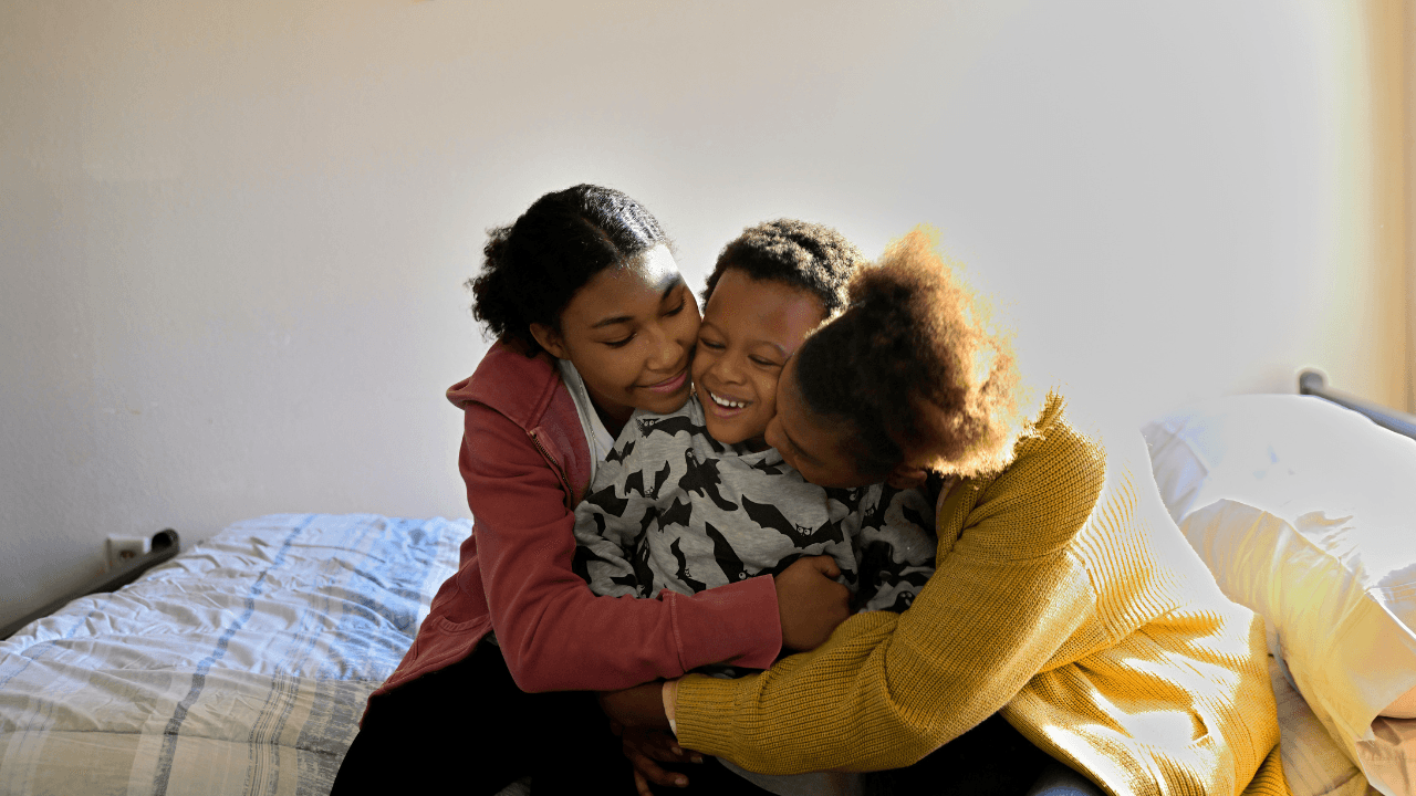Family hugging each other on a bed.