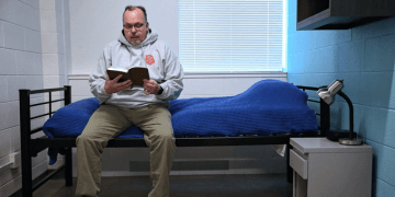 Man reading a book on his bed.