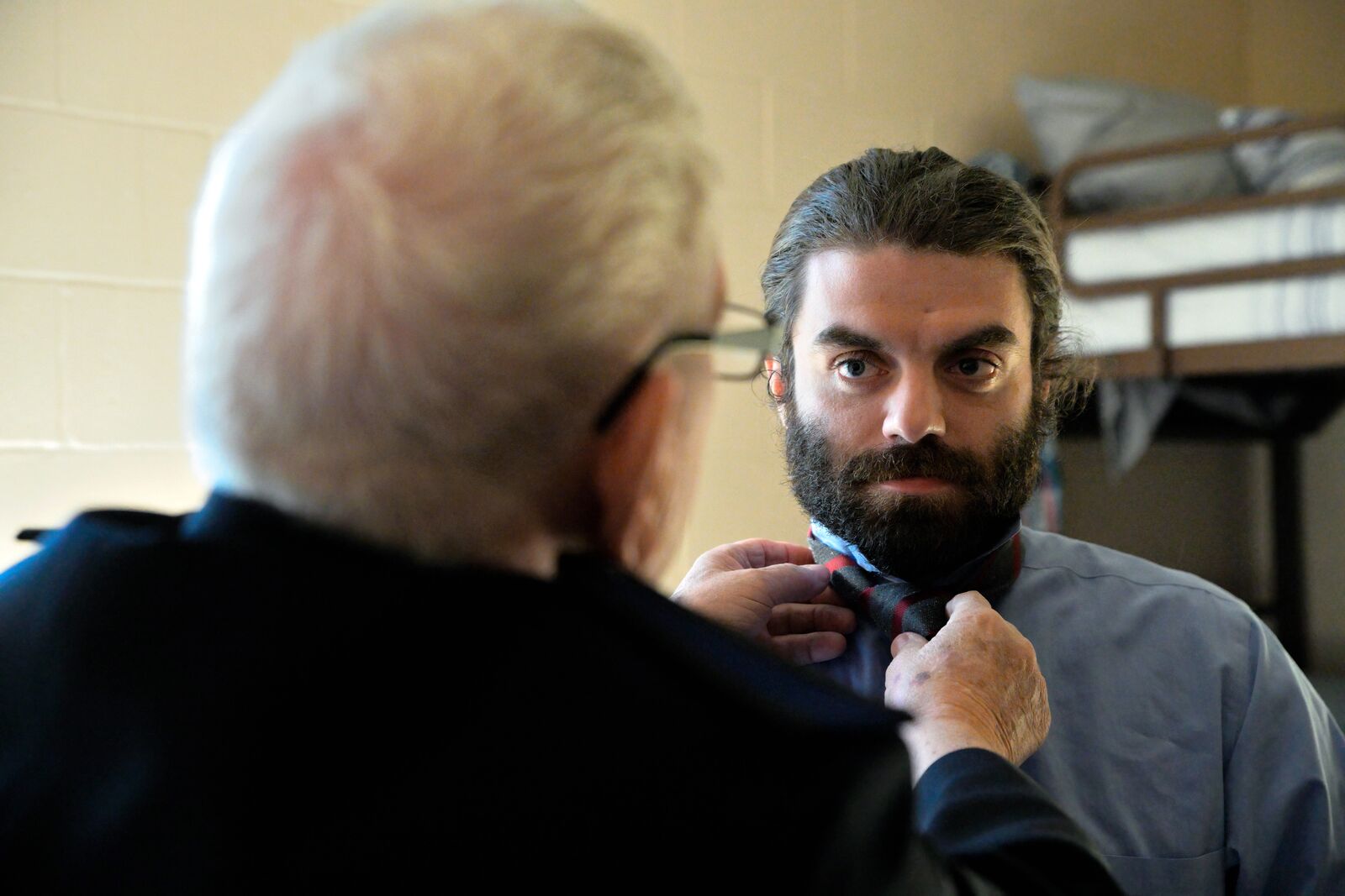 Salvation Army volunteer helping someone tie their tie.
