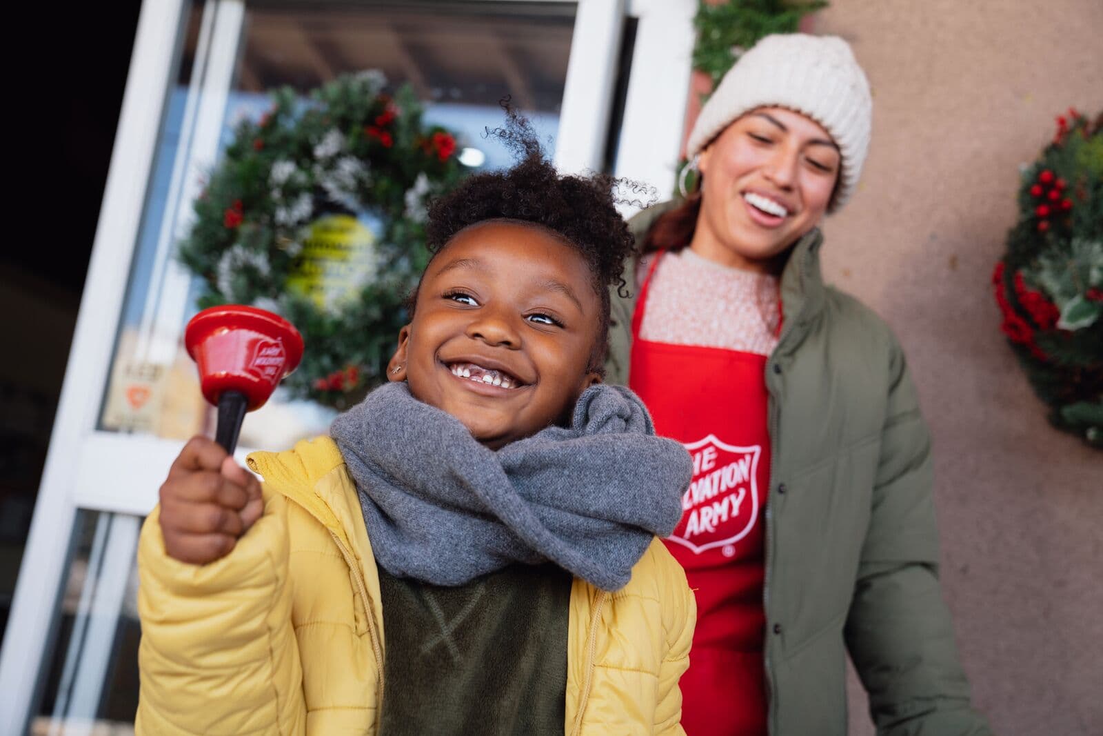 A young girl smiling ringing a bell.